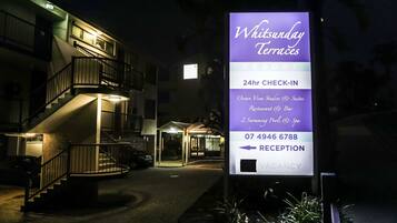 Une enseigne d’hôtel indiquant « Witsunday Terraces » et mentionnant les équipements suivants : « Studios et suites avec vue sur l’océan », « Restaurant et bar », « 2 piscines et spa », ainsi qu’un service d’enregistrement ouvert 24 heures sur 24.