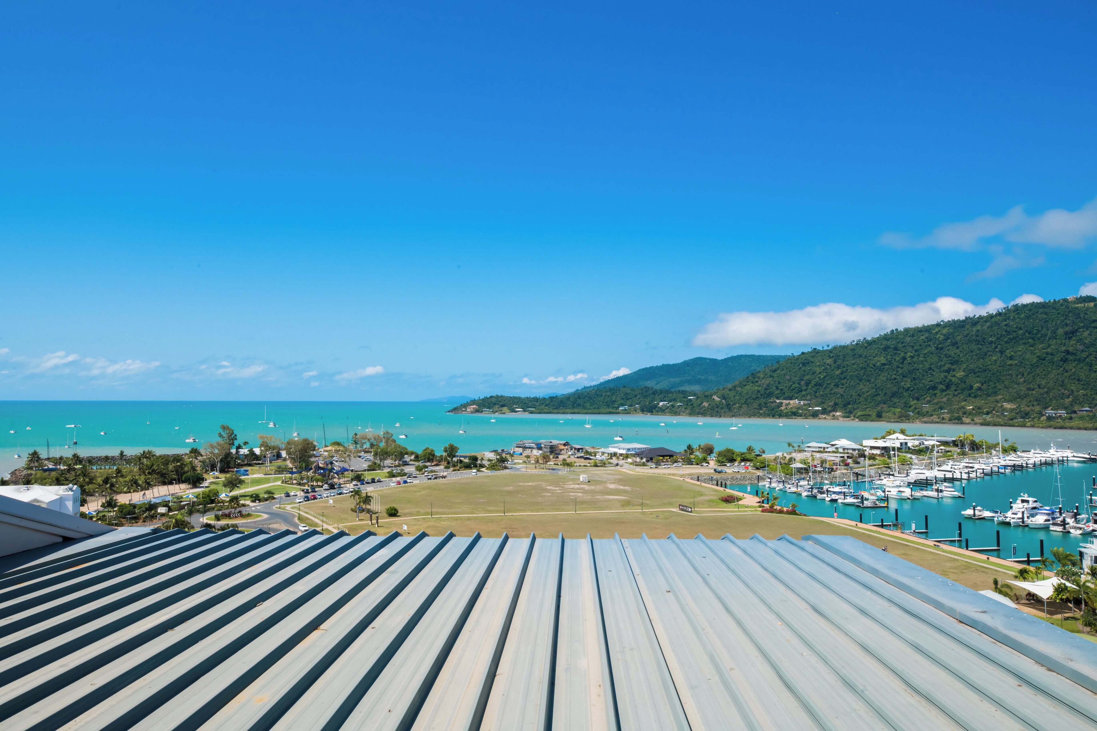 A marina with boats, a clear blue sky, and a view of the ocean.