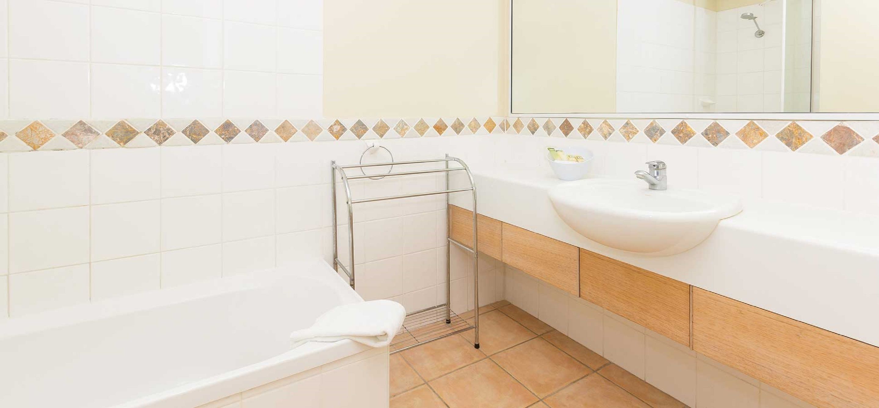 A modern bathroom with a white bathtub, a sink, and a mirror.