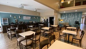 A spacious dining area with multiple tables and chairs, a counter with a cash register, and a mural on the wall. - Sleep Inn And Suites Pearland - Houston South (Pearland)