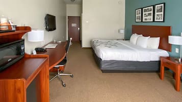 A hotel room with a bed, desk, chair, and a television.
