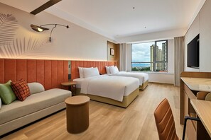 A hotel room with a bed, a sofa, a desk, and a view of buildings.