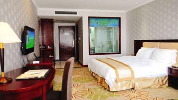 A hotel room with a bed, desk, chair, TV, and a window with a view.