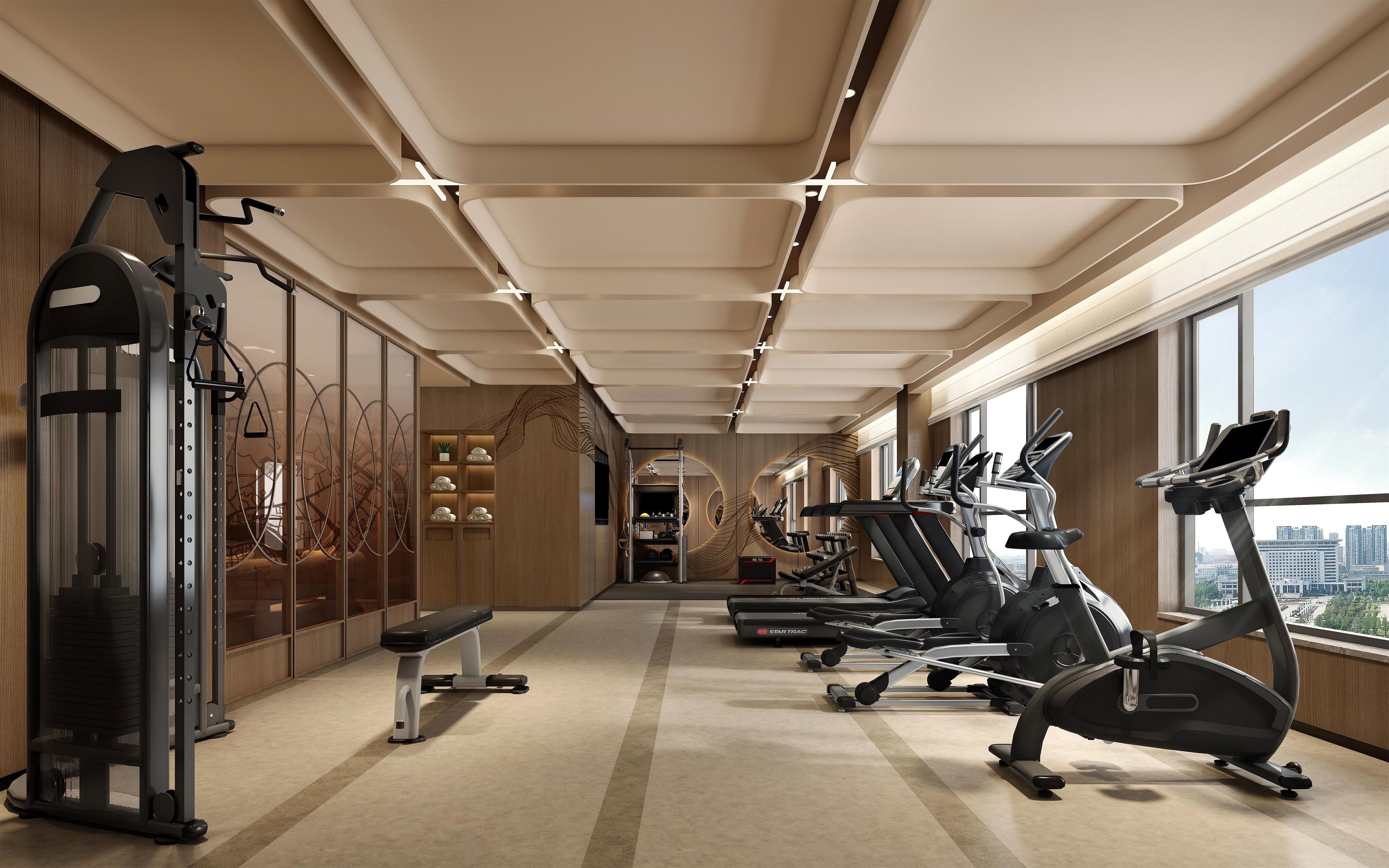 A modern gym with cardio machines, weightlifting equipment, and a bench.