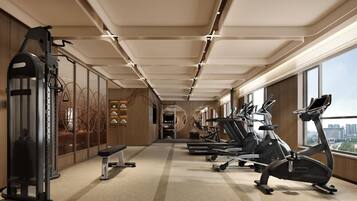 A modern gym with cardio machines, weightlifting equipment, and a bench.