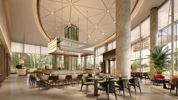 A spacious indoor area with high ceilings, large windows, and a central seating area with tables and chairs.