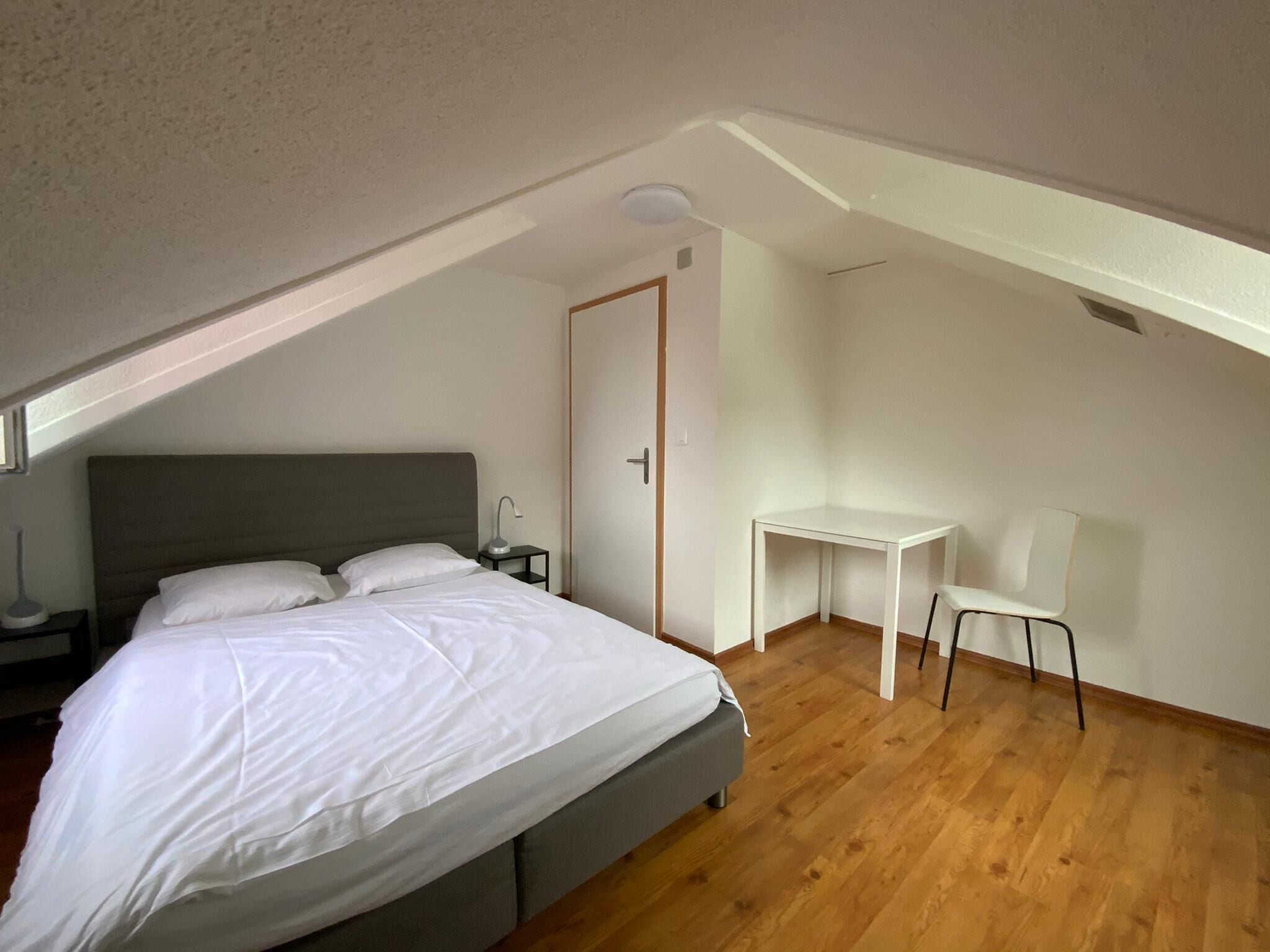 Ein Schlafzimmer mit einem Bett, einem Schreibtisch und einem Stuhl.