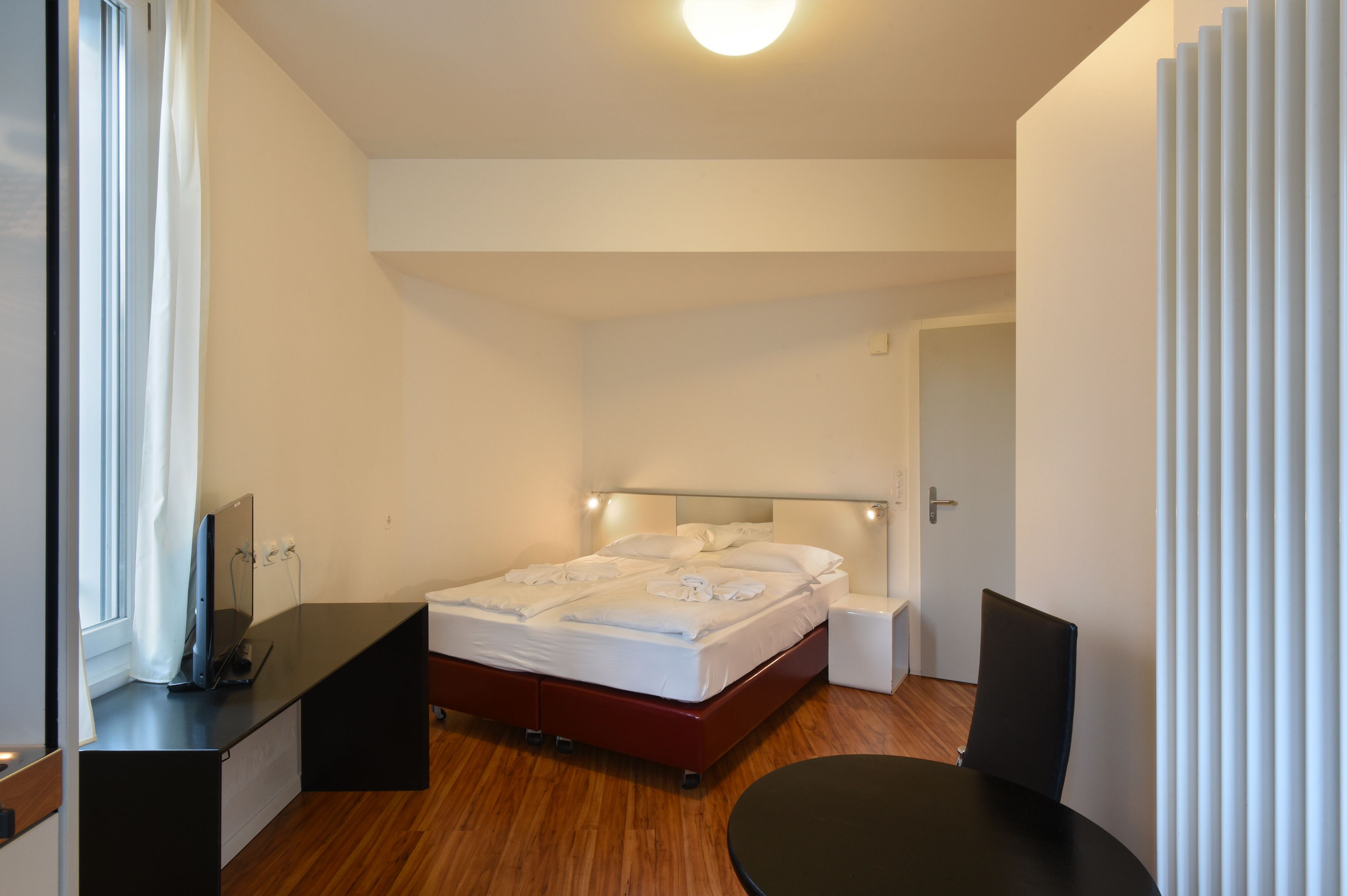 Ein modernes Hotelzimmer mit Bett, Nachttischen, Schreibtisch und Stuhl.