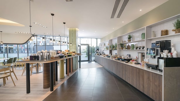 A modern kitchen with a long counter, pendant lighting, and a view of the city. -  Park Inn by Radisson Krakow (Kraków)
