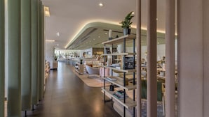 A modern interior with a long corridor, shelves with books and decorative items, and a seating area with a sofa and chairs. -  Park Inn by Radisson Krakow (Kraków)