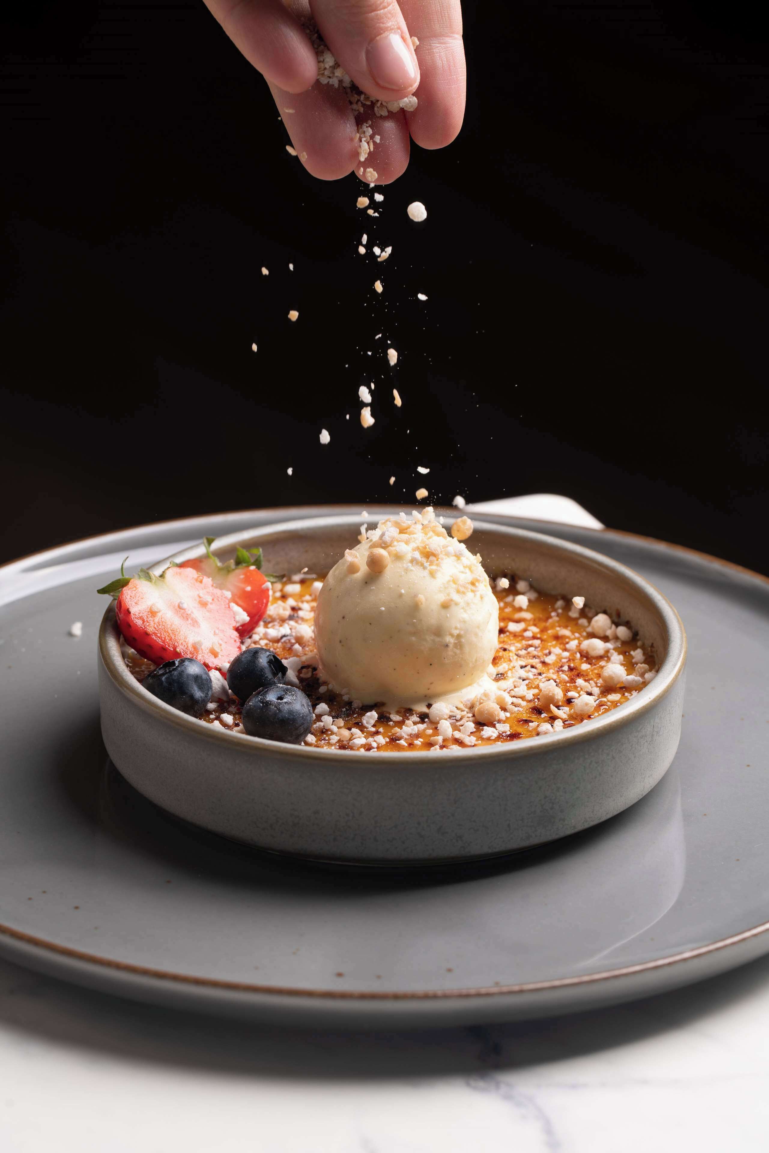 A dessert with ice cream, strawberries, and blueberries on a plate.