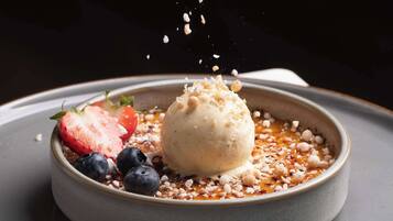 A dessert with ice cream, strawberries, and blueberries on a plate.