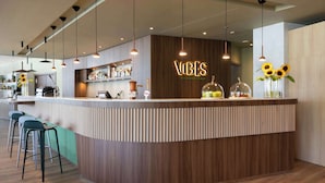 A modern bar area with a curved counter, pendant lighting, and a sign that reads "VIBES Restaurant & Bar". -  Park Inn by Radisson Krakow (Kraków)