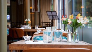 Ein gedeckter Tisch mit klaren Gläsern, einer Kerze und einer Blumenvase.