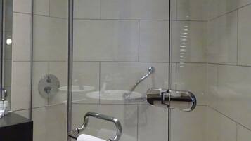Ein modernes Badezimmer mit einer Duschkabine aus Glas, einem schwarzen Waschtisch und einem Handtuchhalter mit einem weißen Handtuch.