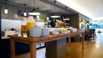 A breakfast buffet with various food items and beverages, a coffee station, and a chalkboard menu.