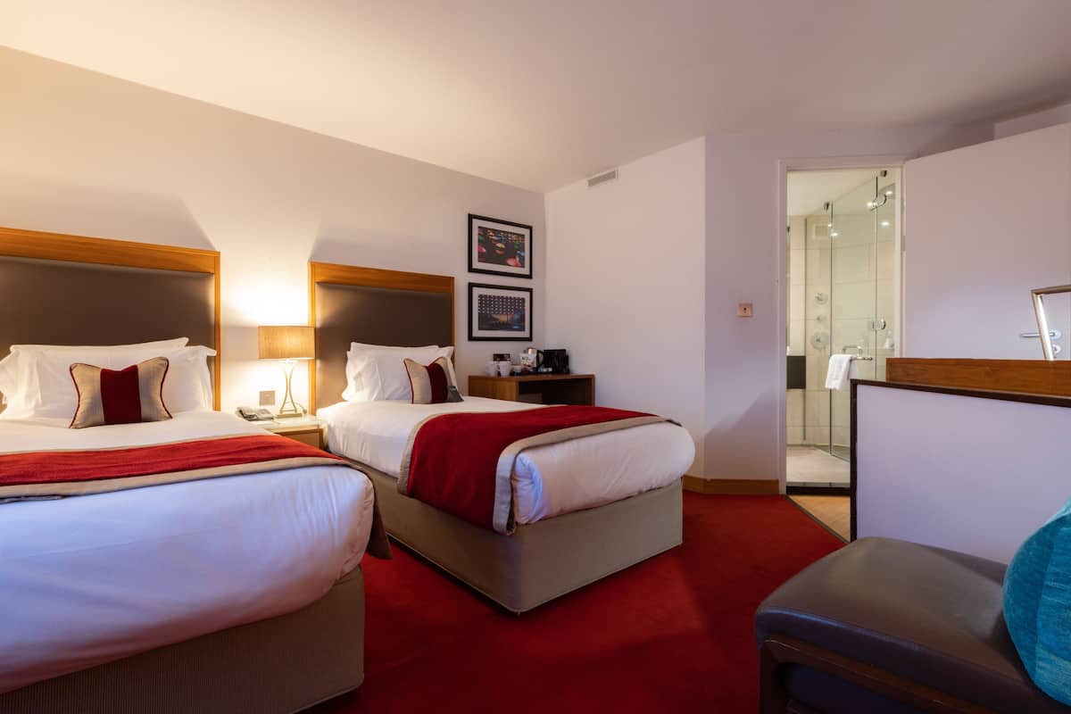 Une chambre d’hôtel avec deux lits, un bureau, une chaise et un espace douche.