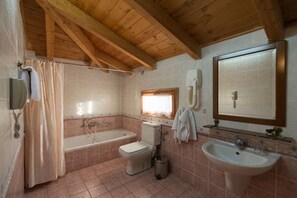 A bathroom with a bathtub, toilet, sink, and a mirror. - King Iniohos (Delphi)