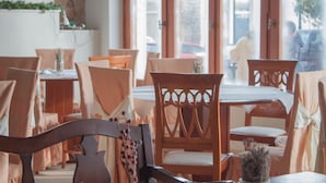 Un interior de restaurante con mobiliario de madera, ventanas amplias y vistas a la calle.