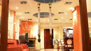 Un vestíbulo de hotel de diseño moderno, con un sofá rojo, un televisor y un comedor con sillas y una mesa.