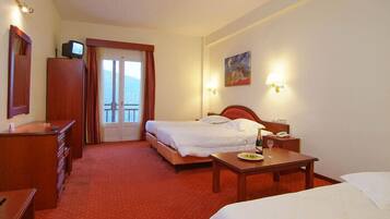 Habitación de hotel con cama, escritorio, silla, televisor y un cuadro en la pared.