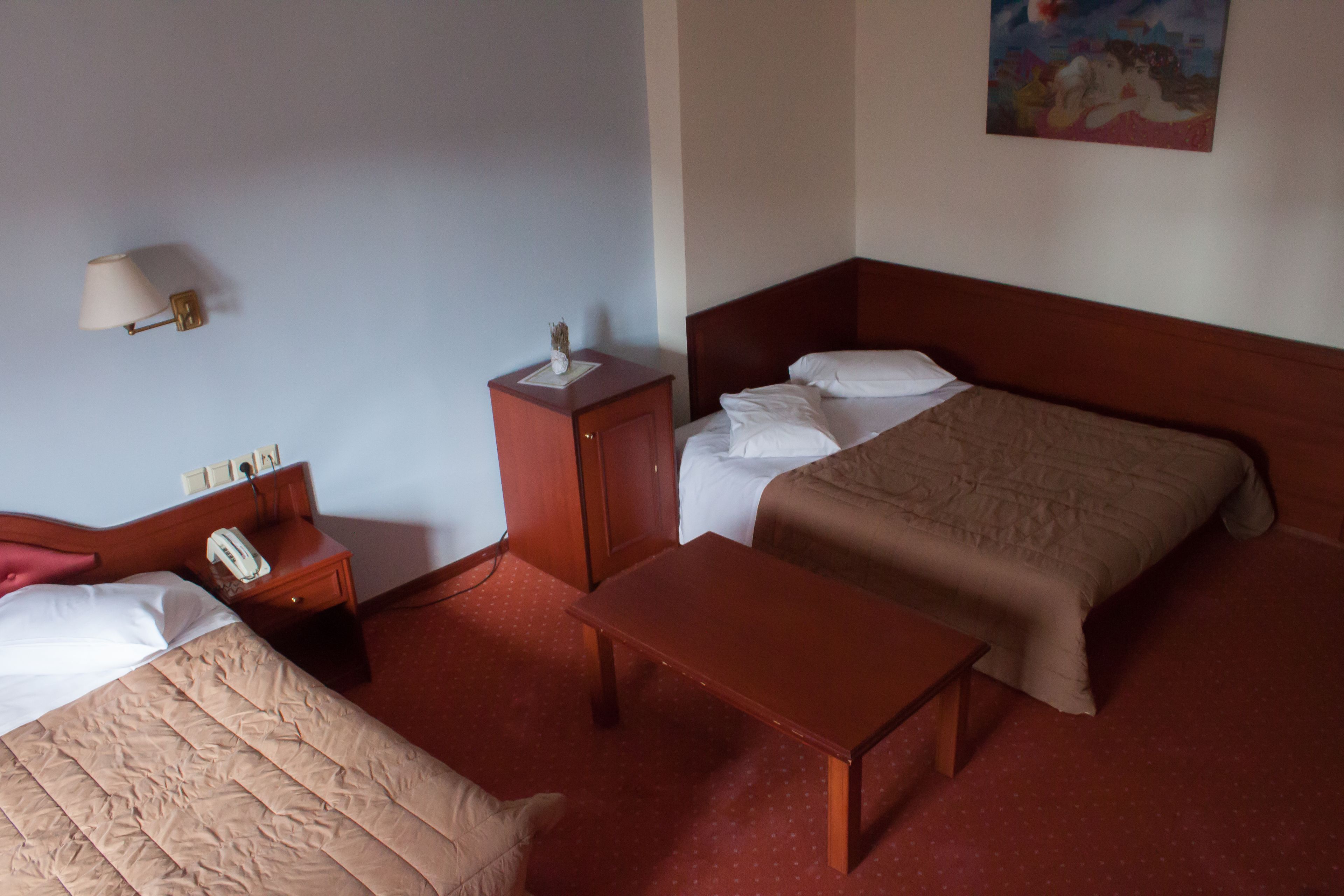 Une chambre d’hôtel avec un lit, une table de chevet, une lampe et un tableau au mur.