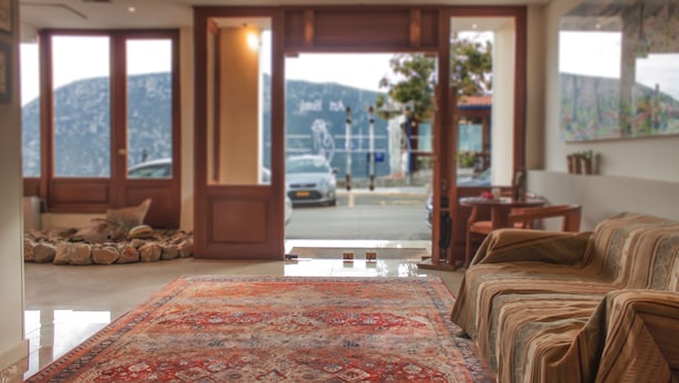 Un salón amplio con un tapete grande, un sofá y vistas a la calle y las montañas a través de puertas abiertas.