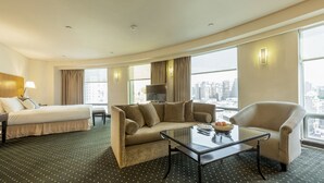 Una habitación de hotel con cama, sofá, mesa de centro y televisión.