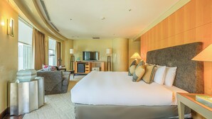 Habitación de hotel con una cama grande, un escritorio, un televisor y un minibar.