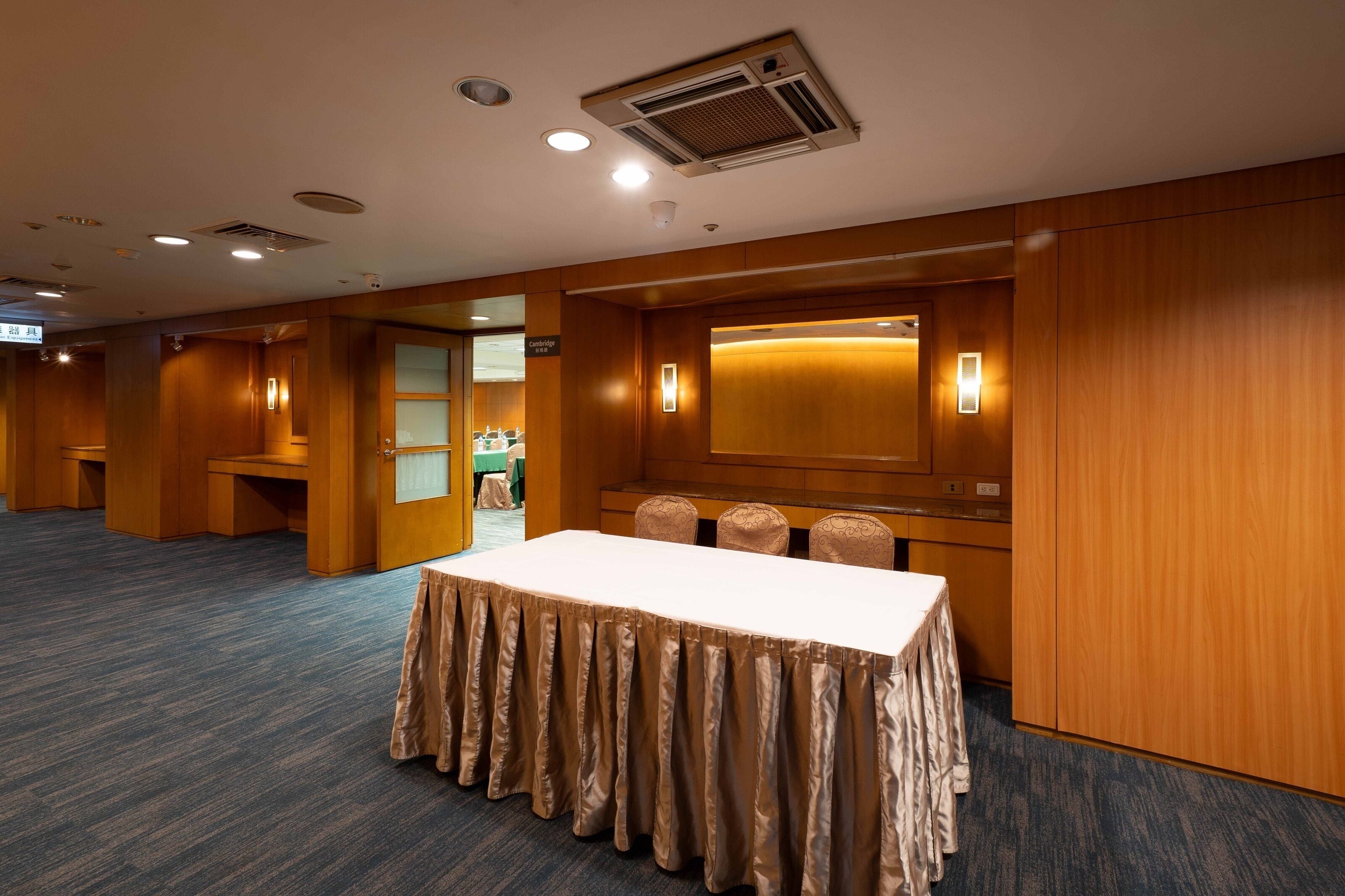 Un salón de conferencias con una mesa larga, paneles de madera e iluminación empotrada.
