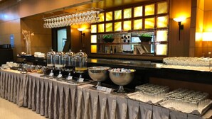 Montaje de bufé con varios recipientes de comida, un candelabro y un fondo con iluminación cálida.