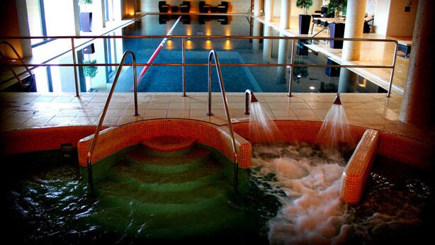 A hot tub area with a glass railing, a pool, and a staircase leading down. - Bicester Hotel Golf and Spa (Bicester)