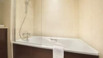Un baño moderno con ducha envuelta en vidrio, bañera blanca y muebles de madera oscura.