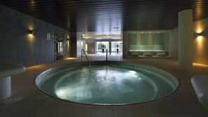 A large indoor swimming pool with a modern design, surrounded by walls and a ceiling with linear patterns. - Bicester Hotel Golf and Spa (Bicester)