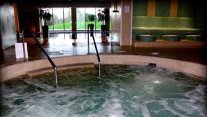 A hot tub with a tiled floor and a bench area in the background. - Bicester Hotel Golf and Spa (Bicester)