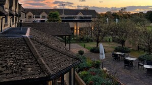 A courtyard with a brick pathway, a small garden, and a building with a sloped roof. - Bicester Hotel Golf and Spa (Bicester)