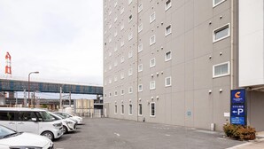 Uma área de estacionamento em frente a um hotel, com uma placa indicando uso para hóspedes.