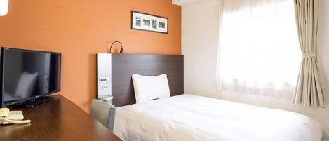 A hotel room with a bed, a desk with a television, a phone, a headboard, and a window with curtains.