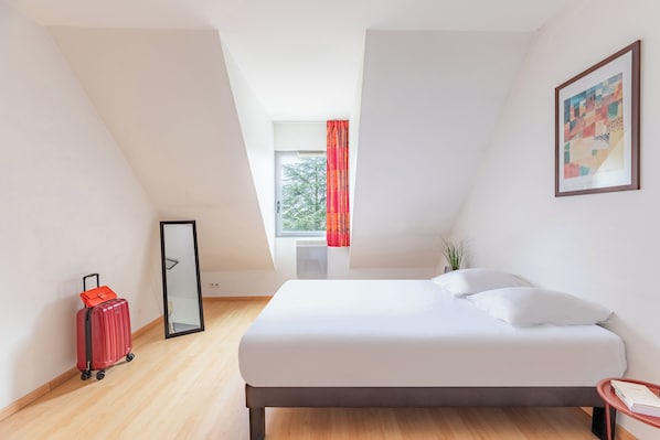 Una habitación de hotel moderna con cama, una maleta roja, una ventana con cortinas y un cuadro en la pared.
