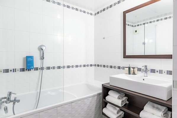 Un baño moderno con bañera, lavamanos y espejo.