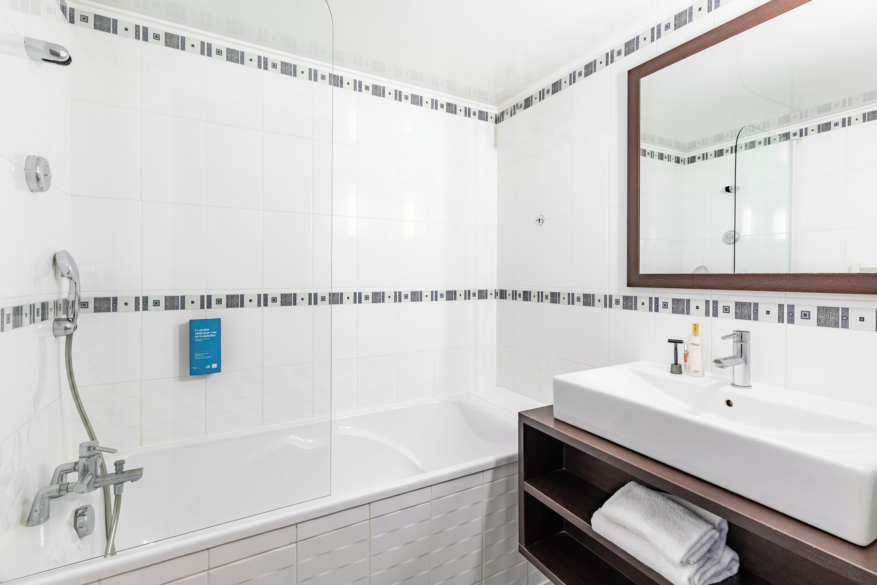 A modern bathroom with a bathtub, a sink, and a mirror.