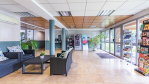 A spacious lobby with a reception desk, seating area, and a glass storefront displaying merchandise.