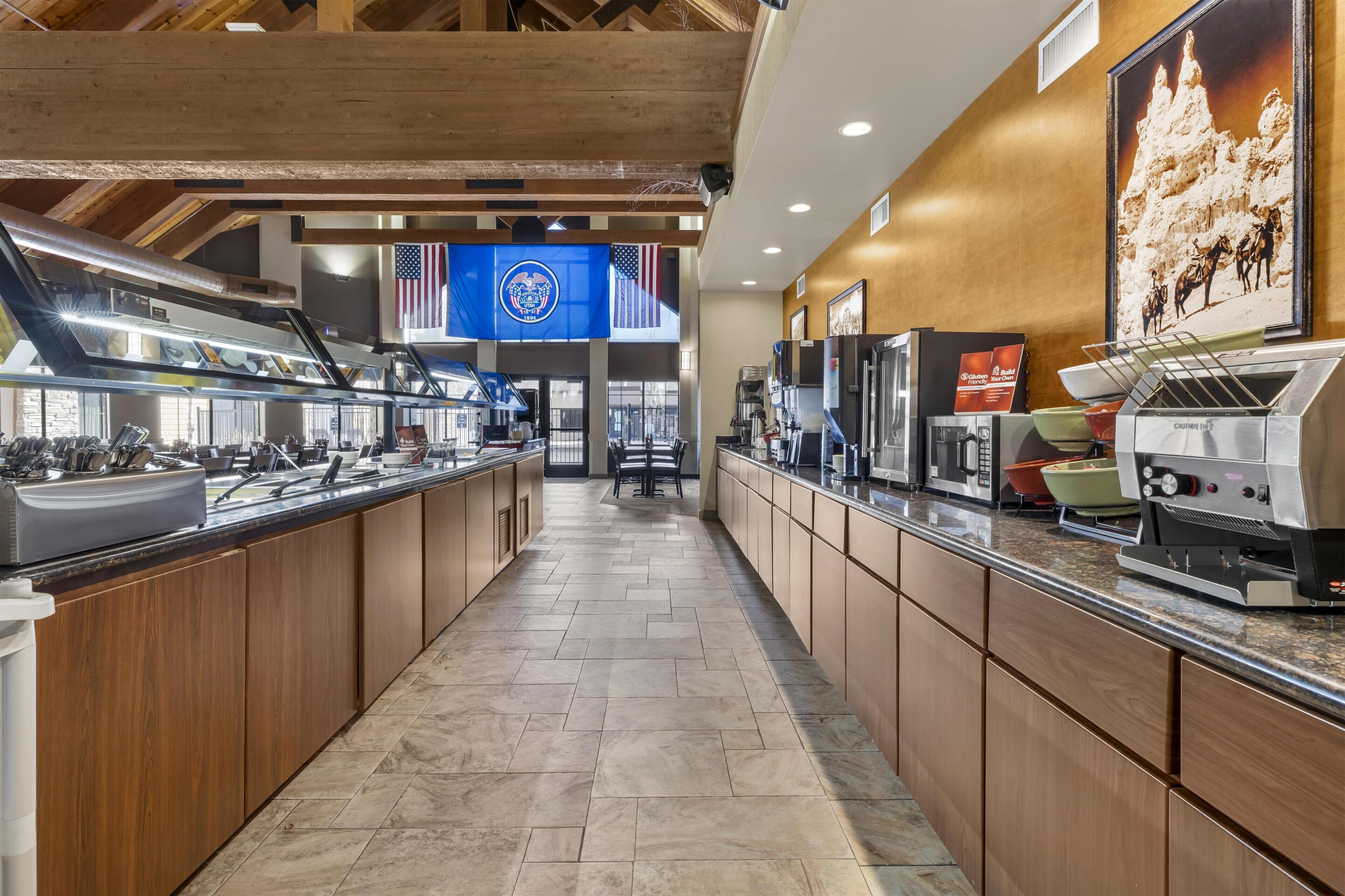 A commercial kitchen with stainless steel appliances, wooden cabinets, and a tiled floor.