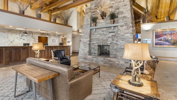 A lobby with a stone fireplace, leather seating, a reception desk, and a map on the wall. - Best Western Plus Bryce Canyon Grand Hotel (Bryce Canyon)