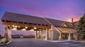 A hotel with a covered entrance, stone pillars, and a view of the mountains. - Best Western Plus Bryce Canyon Grand Hotel (Bryce Canyon)
