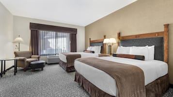 Hotelkamer met een groot bed, een kleiner bed, een bank, een bureau en een raam met gordijnen.