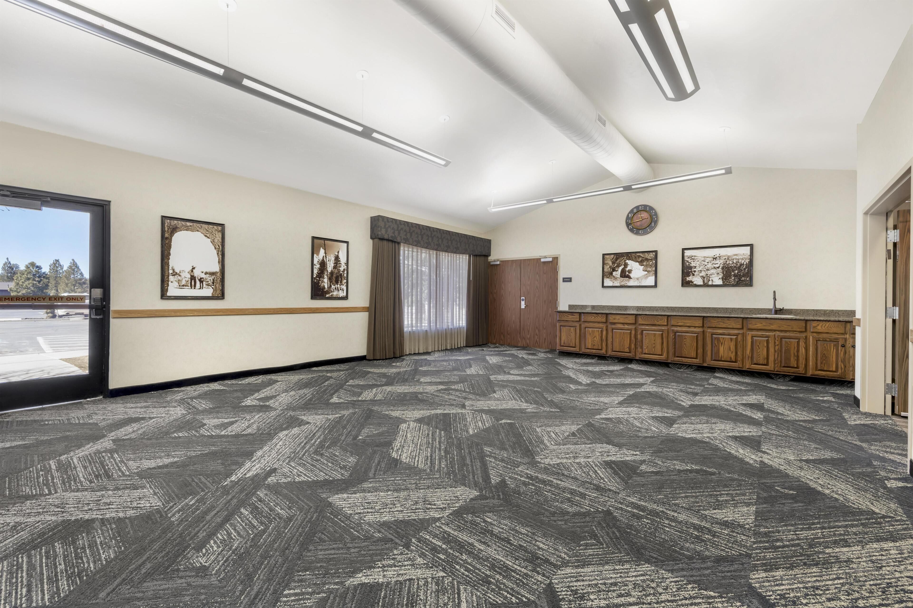 A spacious room with a patterned carpet, wooden cabinets, and framed pictures on the walls.