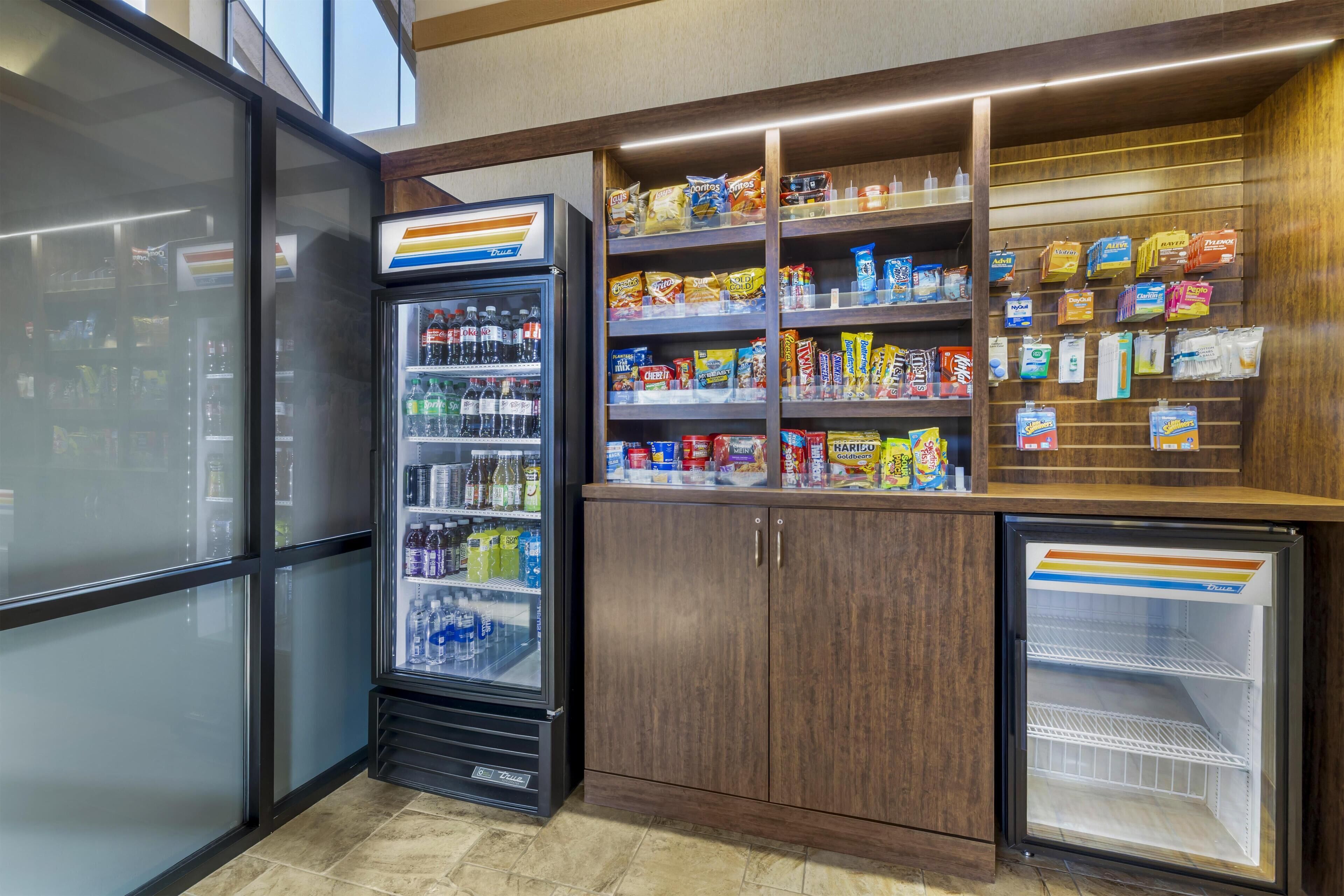 Una vetrina refrigerata con bevande, uno scaffale per snack e un congelatore.