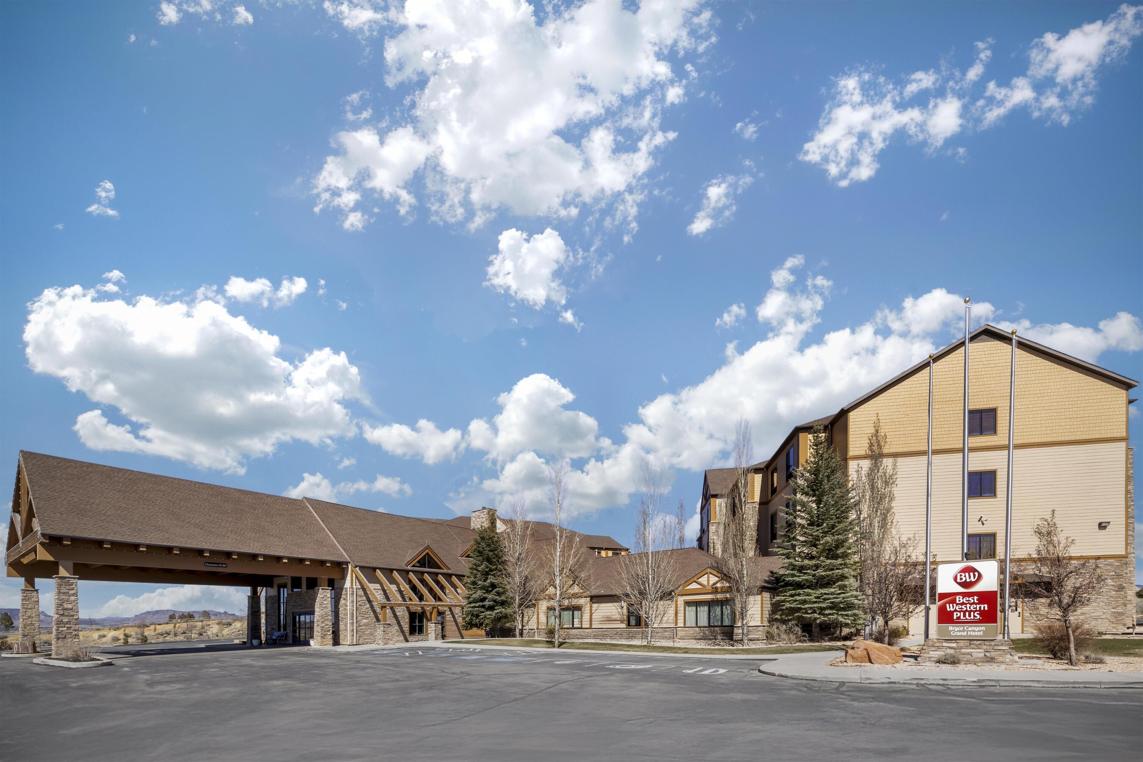 A hotel with a covered outdoor area, a sign indicating it is a Best Western Plus, and a mountainous backdrop.