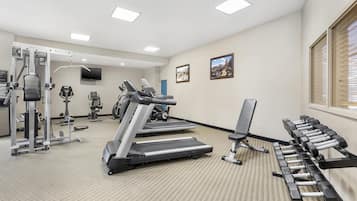 Ein Fitnessstudio mit Laufbändern, Kraftgeräten und Kurzhanteln.